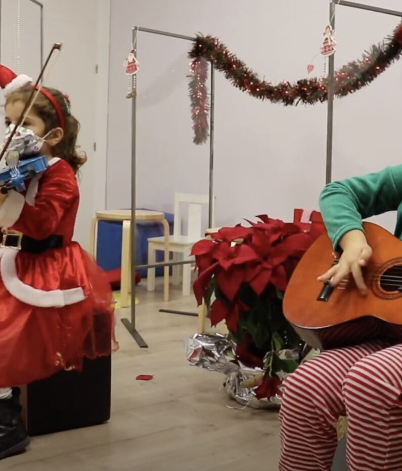 Niñas vestidas de navidad tocando instrumentos